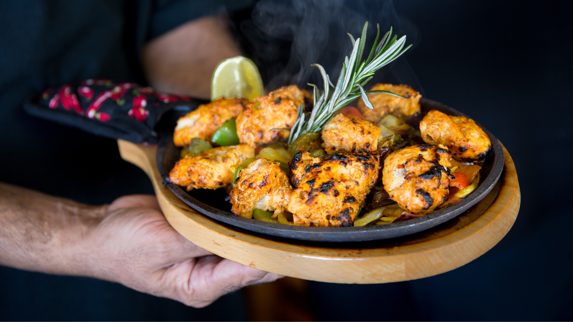 A sizzling platter of tandoori chicken tikka with peppers and rosemary at Marigold Maison